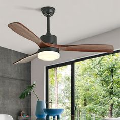 a ceiling fan in a living room next to a table with chairs and vases