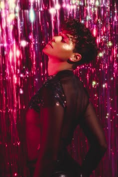 a woman with her eyes closed standing in front of a wall full of shiny lights