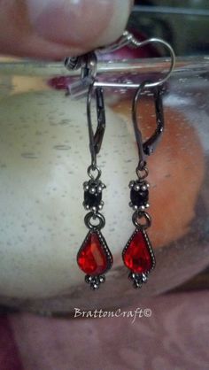 "These red tear drop earrings would look great with a vampire, devil, or sorceress costume! They are made with black Japanese glass beads and red tear drop faceted charms that have some sparkle. The leverback is base metal with a matte black finish. The earrings dangle 1-1/16th inches from the end of the leverback and are about 1/4 inch wide. These earrings are ready to ship and will arrive in a gift box. Check out other BrattonCraft Halloween Jewelry here: https://www.etsy.com/shop/BrattonCraft Red Gothic Jewelry For Party, Gothic Drop Earrings For Formal Occasions, Elegant Red Jewelry For Halloween, Red Gothic Earrings For Pierced Ears, Gothic Handmade Earrings For Party, Handmade Gothic Earrings For Party, Vampire Style Dangle Earrings As Gift, Red Pierced Earrings For Halloween, Red Pierced Halloween Earrings