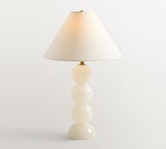 a white lamp sitting on top of a table next to a white wall and floor