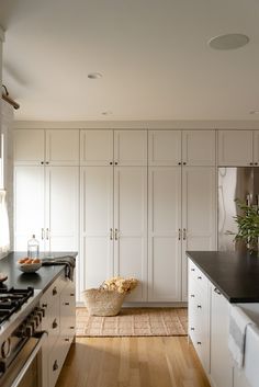 a large kitchen with white cabinets and black counter tops on the island in front of an oven