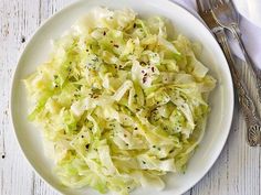 a white plate topped with coleslaw next to a fork