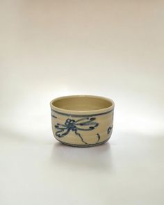 a blue and white bowl sitting on top of a white table next to a wall