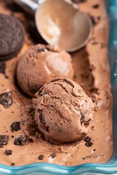 three scoops of chocolate ice cream in a blue dish with oreo cookies on the side