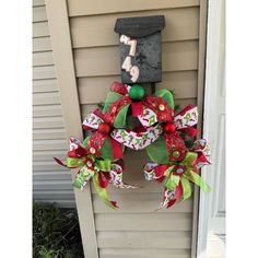 a christmas wreath hanging on the side of a house in front of a mailbox