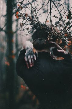 a person with their hands on the back of his head in front of some trees