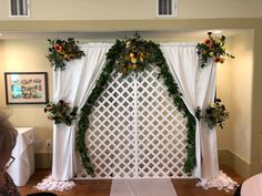 a white backdrop with flowers and greenery on it