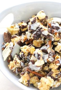 a white bowl filled with chocolate and marshmallows next to a cookie bar