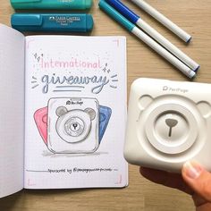 someone holding a camera next to a notebook with an image of a bear on it