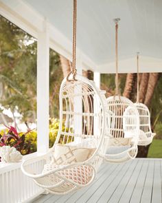 two white hanging chairs sitting on top of a porch