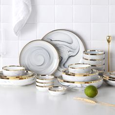 white and gold dinnerware set on counter with lime