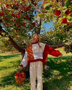 a woman is standing under an apple tree