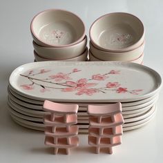 a stack of plates and bowls sitting on top of each other with pink flowers painted on them