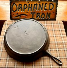 an old cast iron skillet sitting on top of a table next to a sign