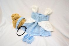 a crocheted baby outfit and booties are laying on a white sheet next to a knitted hat