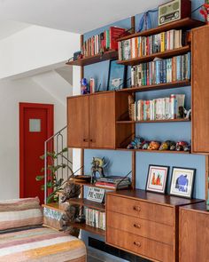 a living room filled with furniture and bookshelves next to a red front door