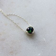 A deep green cubic zirconia, beautifully faceted for maximum sparkle, is set entirely in sterling silver in this versatile necklace, perfect for layering. A slim but sturdy sterling silver chain slides freely through the setting, and the necklace is finished with a simple spring ring clasp. The round faceted emerald CZ measures 6mm in diameter. Choose your perfect necklace (measured end-to-end including clasp) length from the drop-down menu. The last photo shows the same size gemstone and settin Minimalist Sterling Silver Emerald Necklace For May Birthstone, Green Sterling Silver Birthstone Pendant Necklace, Green Pendant Birthstone Necklace In Sterling Silver, Green Sterling Silver Pendant Birthstone Necklace, Minimalist Green Emerald Necklace In Sterling Silver, Green Round Stone Necklace For May Birthstone, Green May Birthstone Necklace With Round Stone, Green Sterling Silver Birthstone Necklace, Green Birthstone Necklace In Sterling Silver