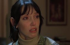 a woman with black hair wearing a turtle neck sweater