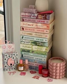 a stack of books sitting on top of a white table next to a vase and other items