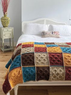 a white bed topped with a multi colored blanket