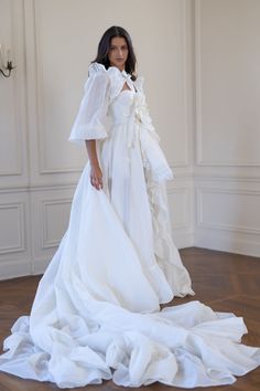 This luxury topper, crafted from crisp silk organdy reminiscent of 1930s haute couture, fastens effortlessly at your waist, transforming any bridal dress into an extravagant gown. Adorned with delicate ruffles that shimmer with each step, it cascades into a sweeping train, the organdy's airy yet structured nature allowing it to float gracefully behind you. Glide down the aisle in full bridal splendour, then detach the tournure to dance freely under the crystal chandeliers. Organdy open-front ski Avant Garde Wedding, Avant Garde Wedding Dress, Wedding Dress Haute Couture, Rooftop Reception, Picturesque Garden, Open Front Skirt, Wedding Dress White, Silk Dressing Gown, Corset Skirt