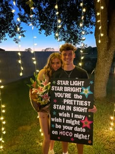 a man and woman standing next to each other holding a sign that says star light you're the prettiest star in sight