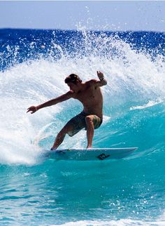 a man riding a surfboard on top of a wave in the ocean with blue water