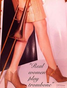 a woman in high heels holding a purse and standing next to a sign that says real women play trombone