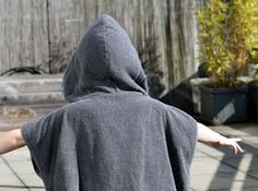 a person in a hoodie throwing a frisbee on the street with their arms outstretched