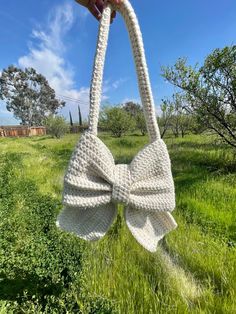 a hand holding a white crocheted bow purse