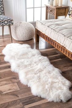 a white sheepskin rug is on the floor next to a bed