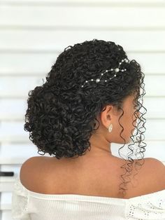 the back of a woman's head with curly hair and pearls in her hair