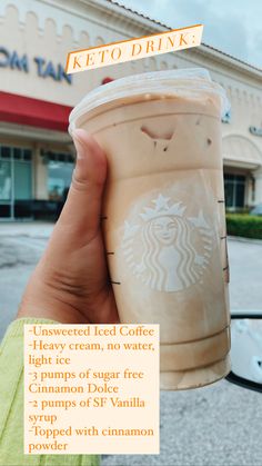 a person holding up a cup of coffee in front of a building with the words keto drink on it