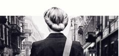 the back of a woman's head as she walks down a city street in black and white