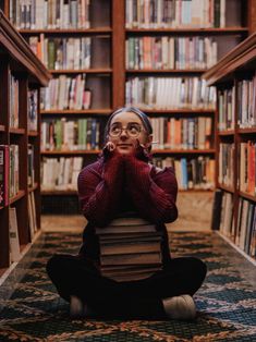 a woman sitting on the floor in front of bookshelves with her hands to her face