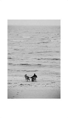 two people sitting in chairs on the beach