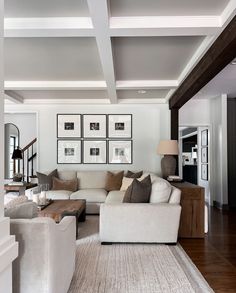 a living room filled with white furniture and pictures on the wall above it's fireplace