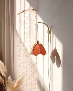 a lamp that is on the side of a wall next to a window with sheer curtains