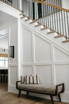 a wooden bench sitting under a stair case