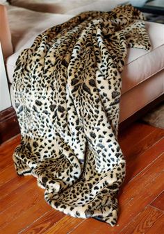 a leopard print blanket sitting on top of a wooden floor next to a white couch