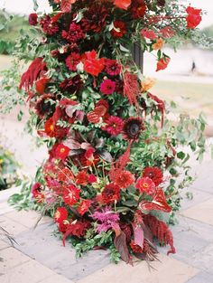 red flowers and greenery are growing on the side of a street light pole in front of a brick walkway