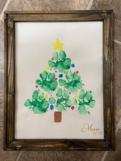 a christmas tree made with handprints is displayed in a frame on the floor