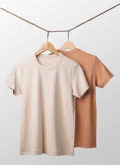 two t - shirts hanging on a clothes line, one in beige and the other in brown