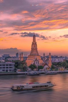 a boat traveling down the river in front of a large building with a spire on top