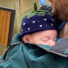 a man holding a baby wearing a knitted hat