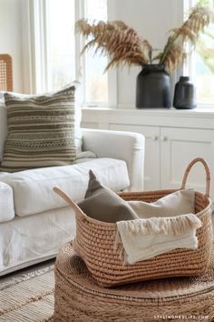 a basket sitting on top of a rug in front of a couch with pillows and blankets