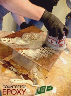 a person using a paint brush to apply epox on a piece of plywood