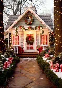 a small house decorated for christmas with wreaths and lights on the front door, surrounded by trees