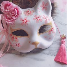 a white cat mask with pink flowers on it