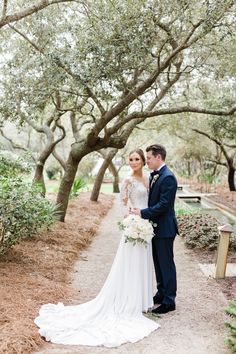 a bride and groom standing in the middle of an oak tree lined path at their wedding